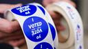 A poll worker holds voting stickers for community members at a school in Allentown.