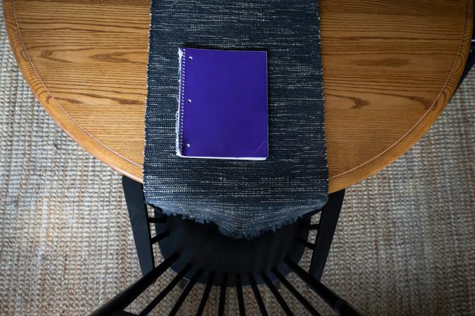 A purple notebook on a dining room table. A purple notebook on a dining room table.