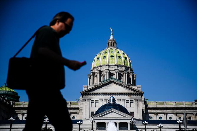 Man walks in front of Pennsylvania state capitol Man walks in front of Pennsylvania state capitol