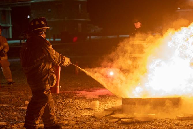 A firefighter puts out a fire during a training class. A firefighter puts out a fire during a training class.