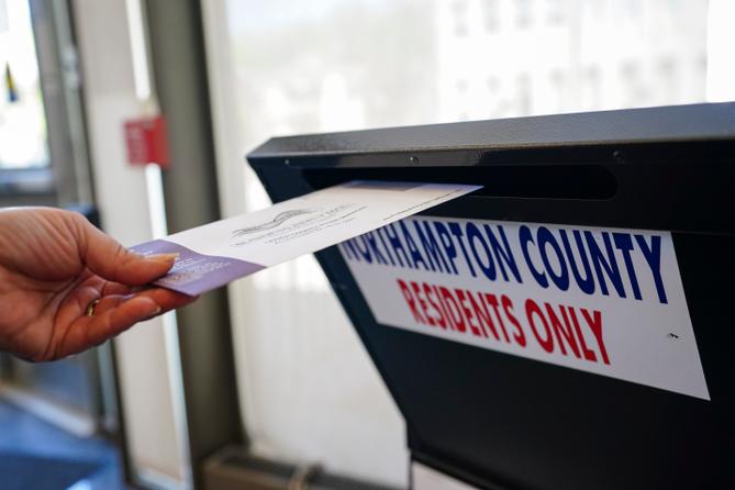 A voter puts a ballot into a drop box on primary Election Day 2024 at Bethlehem City Hall in Northampton County, Pennsylvania.