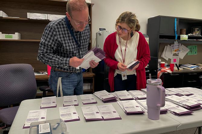 Election clerk Tony Phillips and election intern Maggie Bachman sort the mail ballots received on Election Day into precincts. Election clerk Tony Phillips and election intern Maggie Bachman sort the mail ballots received on Election Day into precincts.
