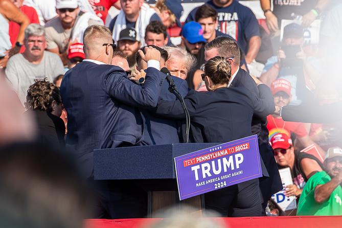 The Secret Service immediately surround former President Trump after he was shot during his campaign stop at the Butler Farm Show grounds on Saturday, July 13, 2024. The Secret Service immediately surround former President Trump after he was shot during his campaign stop at the Butler Farm Show grounds on Saturday, July 13, 2024.