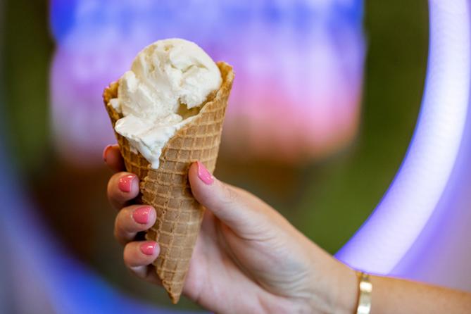 A hand holds a waffle cone with ice cream scoops A hand holds a waffle cone with ice cream scoops