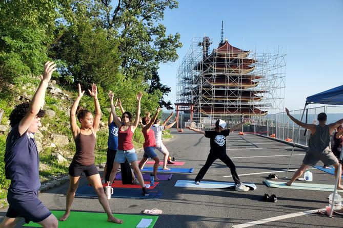 People in yoga poses in front of Reading Pagoda, which is surrounded by scaffolding. People in yoga poses in front of Reading Pagoda, which is surrounded by scaffolding.