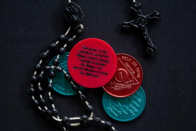 A photo of a rosary and sobriety chips.
