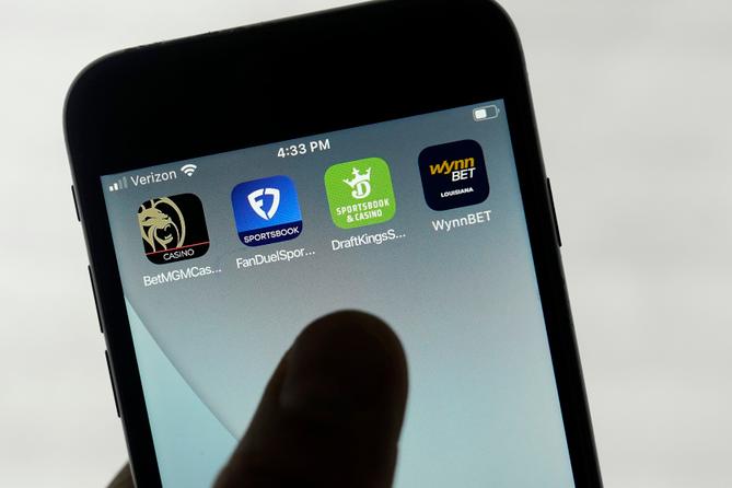 FanDuel, DraftKings, and other online gambling apps are displayed on a phone. FanDuel, DraftKings, and other online gambling apps are displayed on a phone.