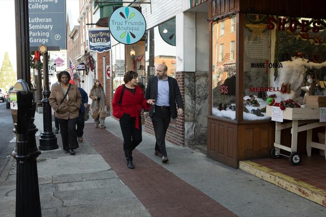 Department of Community and Economic Development Secretary Rick Siger (right) walks past shops in downtown Gettysburg, guided by Jill Sellers (left), president of Main Street Gettysburg.