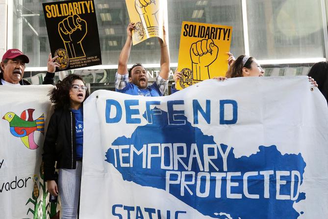 Supporters of temporary protected status immigrants hold signs and cheer at a rally in 2018.