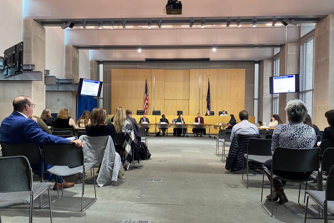 Department of Health officials seated at a public meeting. Department of Health officials seated at a public meeting.