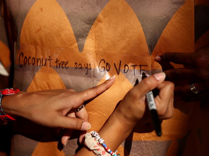 Devisha Bisaria, campus organizer for Project 26, writes “Coconut tree says go vote” on the coconut tree outfit of University of Pittsburgh student Kamal Miya on the campus of the University of Pittsburgh on Nov. 5., 2024. Devisha Bisaria, campus organizer for Project 26, writes “Coconut tree says go vote” on the coconut tree outfit of University of Pittsburgh student Kamal Miya on the campus of the University of Pittsburgh on Nov. 5., 2024.